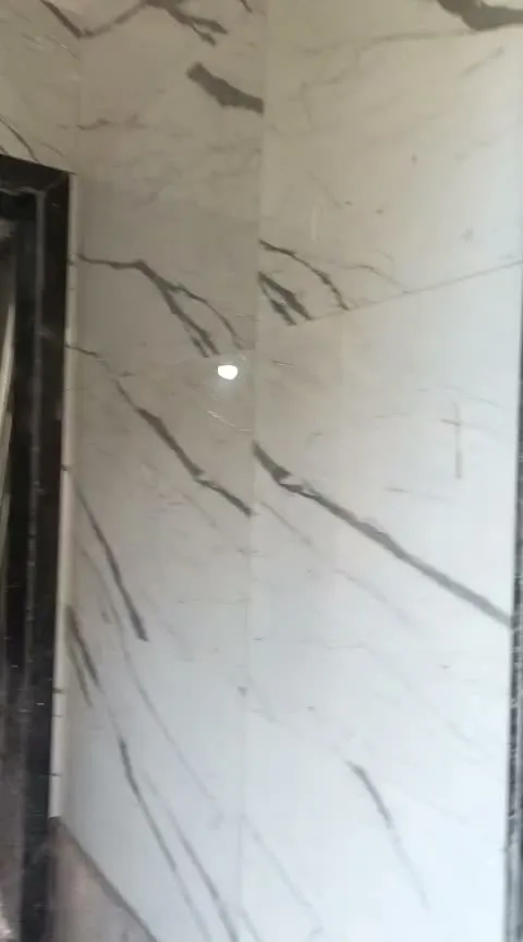 Statuario marble-look wall cladding with black granite door frame